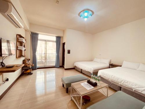 a hotel room with two beds and a table at Xinzhan 23 B&B in Taitung City