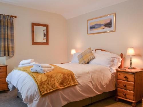 a bedroom with a bed and a dresser and a mirror at Scalelands Cottage in Frizington