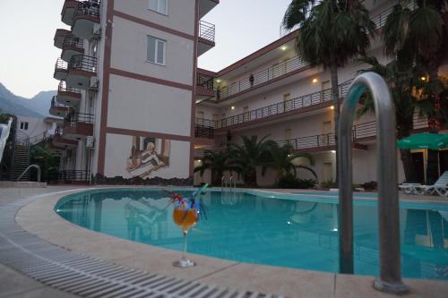 een zwembad van het hotel met een drankje naast een gebouw bij Aybel İnn Hotel in Beldibi