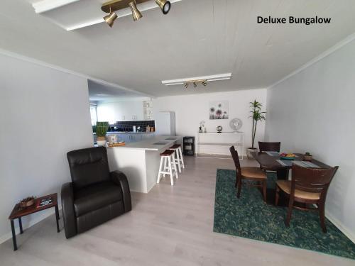 a kitchen and a living room with a table and chairs at Milkwood Country House in Port Elizabeth