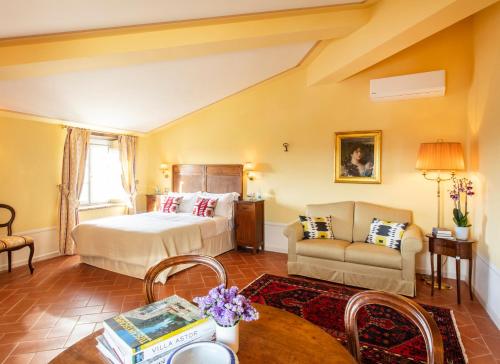 a bedroom with a bed and a couch and a table at Palazzo Tiglio - A Small Luxury Hotels of the World in San Pancrazio