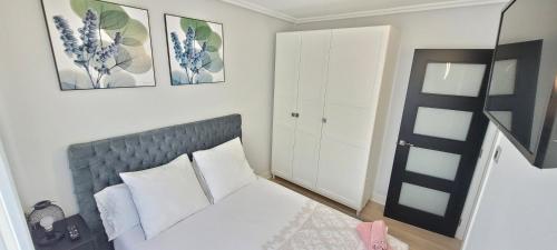 1 dormitorio con 1 cama con almohadas blancas y cuadros en la pared en Artaza Home, en Sopelana