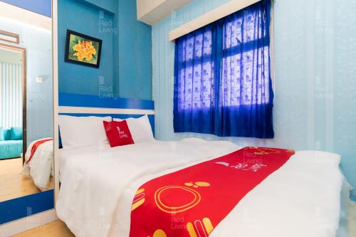 a bedroom with blue walls and a bed with a red blanket at RedLiving Apartemen The Suites Metro - Prisma in Bandung