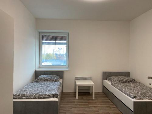 - 2 lits dans une chambre avec une table et une fenêtre dans l'établissement Ubytování Rapotín, à Rapotín