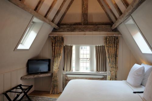 a bedroom with a bed and a tv and windows at Relais Bourgondisch Cruyce, A Luxe Worldwide Hotel in Bruges