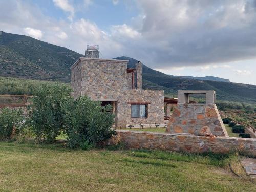 a stone house in a field with mountains in the background at Villa Kore Elafonissi in Ãyios FÃ³tios