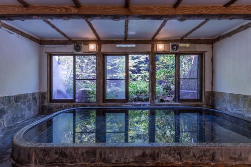 an indoor pool in a house with windows at Ichinoyu Honkan in Hakone
