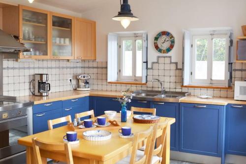 a kitchen with blue cabinets and a wooden table at TΟRRE DI PIETRA-LUXURY RESIDENCE-ΑMAZING SEA VIEW in Marathón