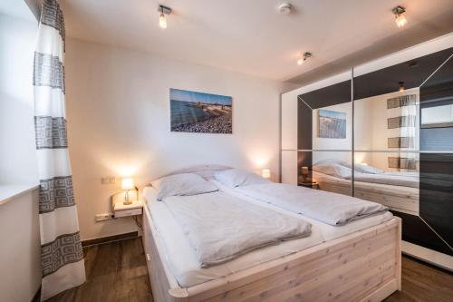 ein Schlafzimmer mit einem großen Bett und einem Spiegel in der Unterkunft Haus Deichkieker Apartment 1 4 in Büsum