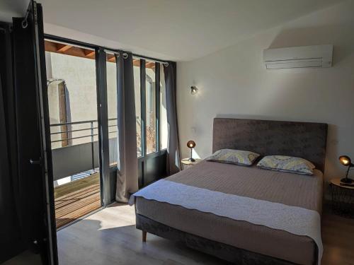 une chambre avec un lit et un balcon dans l'établissement La Bastide de Gabin / ConciergerieDameCarcas, à Carcassonne