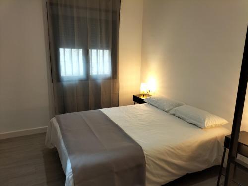 ein Schlafzimmer mit einem weißen Bett und einem Fenster in der Unterkunft Apartamento a estrenar Sevilla centro, Trastamara 19 in Sevilla