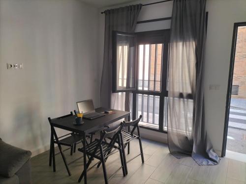 ein Tisch mit Stühlen und ein Laptop neben einem Fenster in der Unterkunft Apartamento a estrenar Sevilla centro, Trastamara 19 in Sevilla