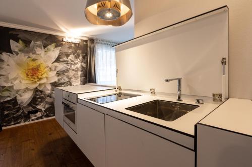 eine Küche mit einem Waschbecken und einer großen Blume an der Wand in der Unterkunft Home Hotel Arosa in Arosa