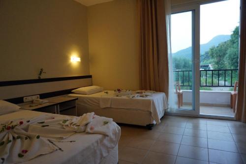 een hotelkamer met 2 bedden en een groot raam bij Aybel İnn Hotel in Beldibi