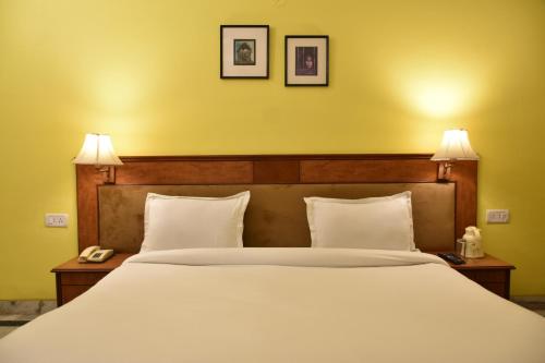 a bedroom with a large white bed with two lamps at Greenwood Hotel in Khajurāho