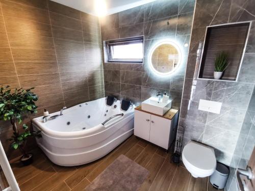 ein Badezimmer mit einer Badewanne, einem WC und einem Waschbecken in der Unterkunft NOVA House Apartments in Delniţa