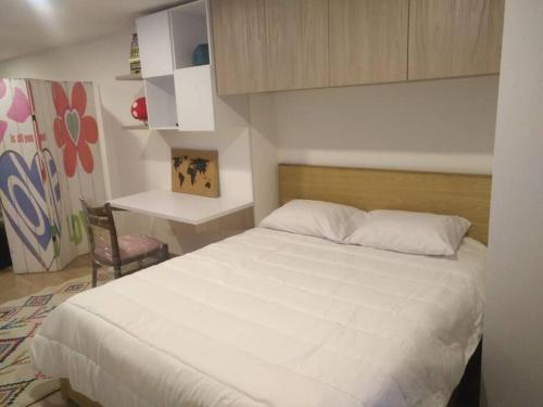 Un dormitorio con una cama blanca y un escritorio. en Hermoso mini apartamento en el corazón de Bogotá, en Bogotá