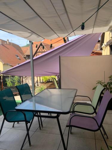 una mesa y sillas bajo una sombrilla en un patio en Gite Les Clés des Vignes, en Dambach-la-Ville
