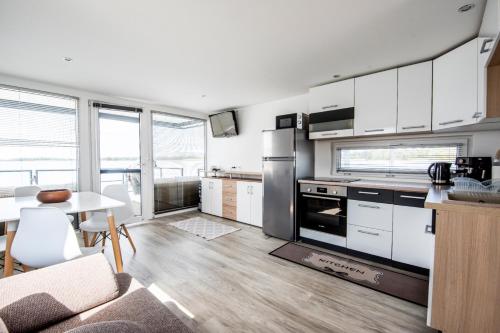 a kitchen with white cabinets and a table and a kitchen with a stove at Panoráma Úszóház 2 in Abádszalók
