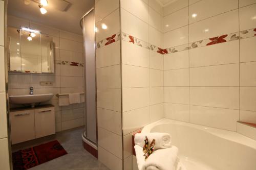 ein weißes Badezimmer mit einer Badewanne und einem Waschbecken in der Unterkunft Almliesl LEOG-685 in Leogang