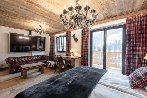 a bedroom with a bed and a couch and a chandelier at Belvedere Elite in Canazei