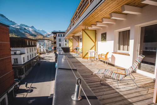 a balcony with chairs and tables on a building at Home Hotel Arosa in Arosa