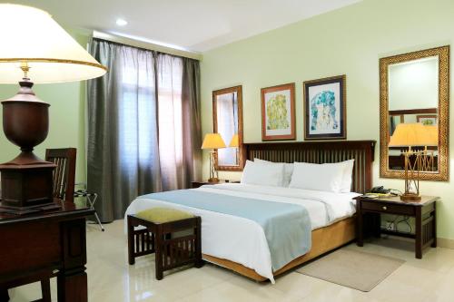 a bedroom with a bed and a desk and a mirror at Hotel Terminus Maputo in Maputo