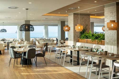 een restaurant met tafels en stoelen met de oceaan op de achtergrond bij INNSiDE by Meliá Costablanca - Adults recommended in Benidorm