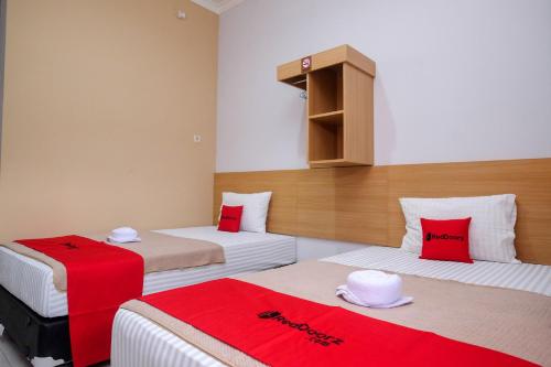 duas camas num quarto com lençóis vermelhos e brancos em RedDoorz Syariah near Perempatan Kartasuro em Surakarta