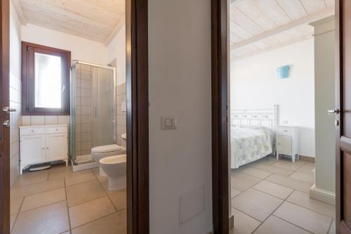 a bathroom with a toilet and a bed in a room at Nuovo Attico in Centro in Villasimius