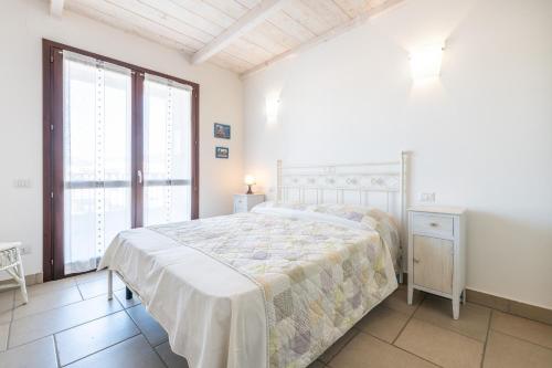 a bedroom with a bed and a large window at Nuovo Attico in Centro in Villasimius