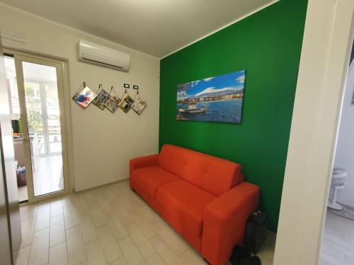 sala de estar con sofá naranja en una pared verde en Acitrezza Vacanze Mare, en Aci Castello