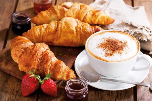 a plate of croissants and a cup of coffee and strawberries at Diecizero Affittacamere in Barùmini