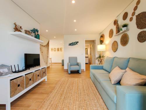 a living room with a blue couch and a tv at Pé Na Duna - beachfront apartment in Viana do Castelo