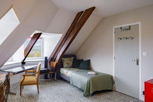 ein Schlafzimmer mit einem Bett und einem Schreibtisch im Dachgeschoss in der Unterkunft Panorama sur le Château de Carrouges in Carrouges
