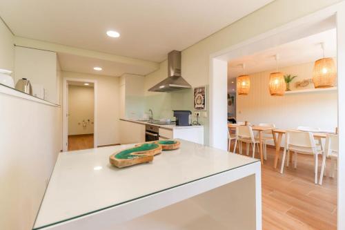 a kitchen with a white counter and a dining room at Pé Na Duna - beachfront apartment in Viana do Castelo