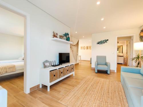 a room with a bed and a tv and a couch at Pé Na Duna - beachfront apartment in Viana do Castelo