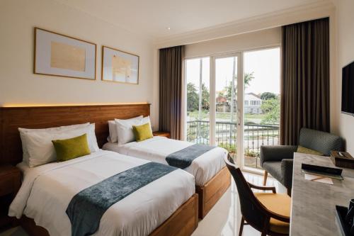 Una habitación de hotel con dos camas y balcón. en Umpadhi Canggu, en Canggu