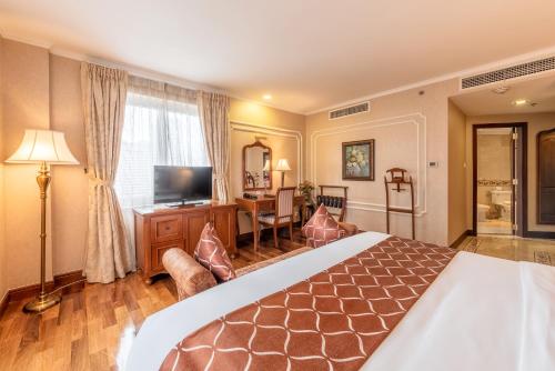 a hotel room with a large bed and a television at Hotel Grand Saigon in Ho Chi Minh City