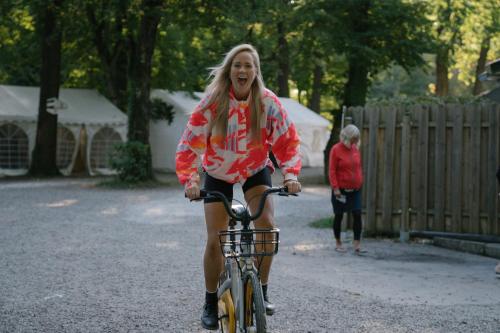 a woman riding a bike down a road at Munich Central Camping in Munich