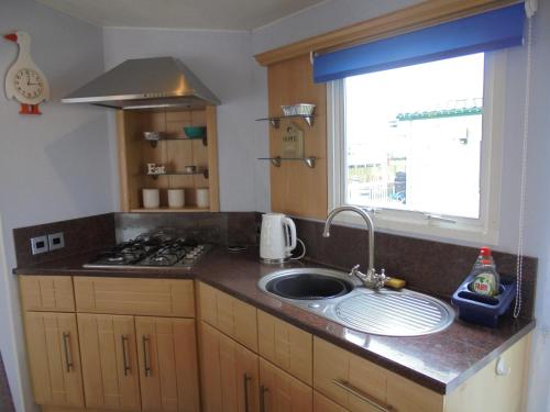 a kitchen counter with a sink and a window at The Chase Topaz Super 4 Berth panel heated Wrap around veranda in Ingoldmells