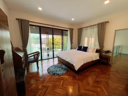 a bedroom with a bed and a large window at Thanawan Villa 素贴山下 清迈大学旁的独栋泳池别墅 in Chiang Mai