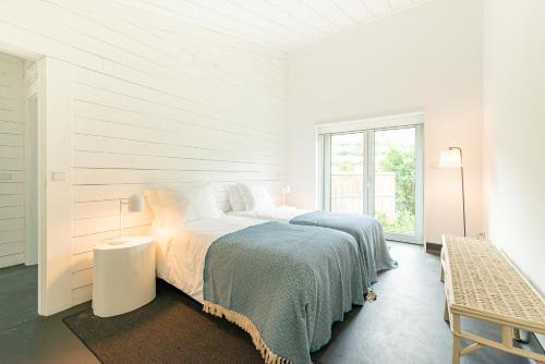 a white bedroom with a large bed and a window at Casas da Prainha B in Santo Amaro