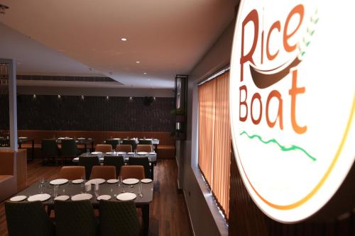 a restaurant with tables and chairs and a red boat sign at Hotel Grand Alleppey in Alleppey