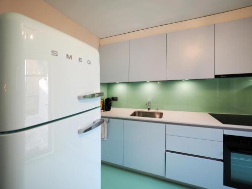 a white kitchen with a sink and a refrigerator at Rustico Mulino1 - Fully Renovated Near Locarno and Ascona in Minusio