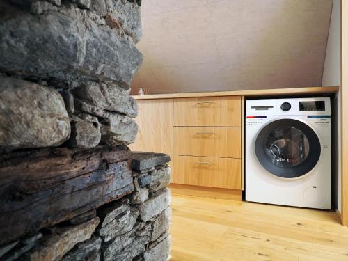 - un lave-linge et un sèche-linge dans une pièce dotée d'un mur en pierre dans l'établissement Rustico Mulino1 - Fully Renovated Near Locarno and Ascona, à Minusio
