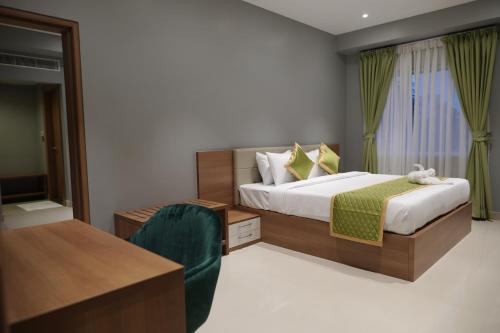 1 dormitorio con cama, escritorio y silla en Hotel Grand Alleppey, en Alleppey