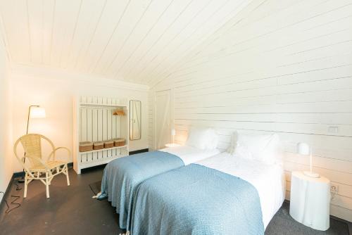 a white bedroom with a bed and a chair at Casas da Prainha C in Canto da Areia