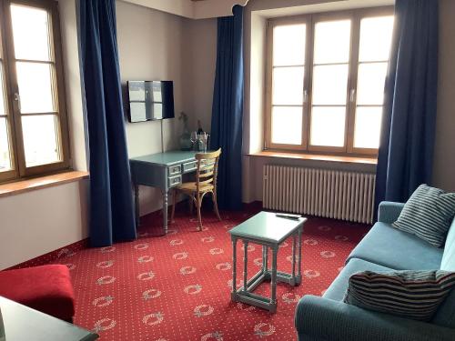 a living room with a desk and a couch at Strandhotel Berg in Berg am Starnberger See