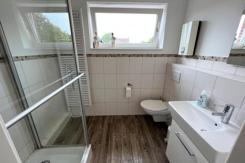 ein Bad mit einem WC, einem Waschbecken und einem Fenster in der Unterkunft Whg Lütt Lee Sandwall 60 Wyk in Wyk auf Föhr
